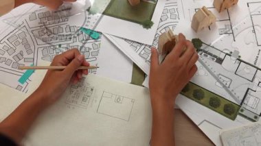 Mimar ve mühendis, mimari belge, ölçüm aracı ve ahşap bloğu ofis çevresinde dağıtan planlar kullanarak inşaat inşaatı hakkında düşünür veya tartışır. Tanımlama.