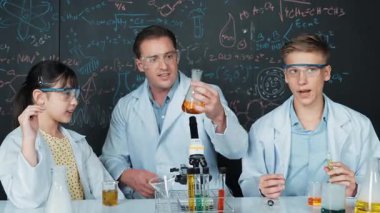 Akıllı öğretmen deney kabında çözeltiyi tutarken öğrenci BTMM fen dersinde kimya teorisiyle karatahta deney yapıyor. Kimyasal sıvıyı laboratuvarda inceleyen yetenekli bir bilim adamı. Öğretim