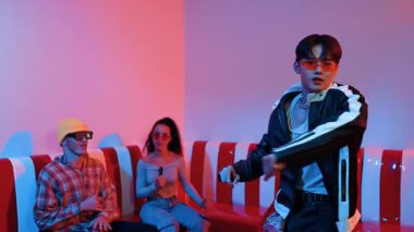 Asyalı bir adam pop müzikle dans ederken, çok kültürlü bir arkadaş evde ışık altında oturuyor. Çekici bir sokak dansçısı kameraya bakarken hip hop müzik dinliyor. Mutluluk.