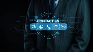 Profesyonel bir işadamı karanlık bir arkaplan karşısında takım elbise içinde duruyor, iletişim seçeneklerini vurgulayan, iletişimin etkinliğini artıran dijital bir arayüz sergiliyor. Dörtgen