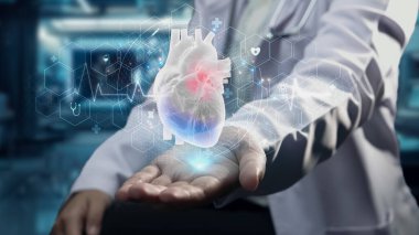 Akıllı doktorların oturduğu ve laboratuvarda elinde kalp hologramının bulanık bir şekilde yüzdüğünü gösteren yakın plan. Sağlık çalışanı teşhisi koydu ve kalp ameliyatına hazırlanıyor. Teknoloji. İyileştirici.