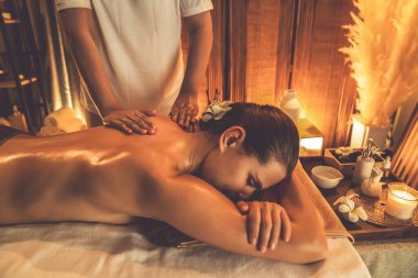 Beyaz kadın müşteri stres önleyici spa masajının keyfini çıkarıyor ve lüks otel ya da otelde sıcak mum ışığında güzellik teniyle eğleniyor. Sessiz.