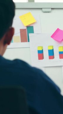 Genç bir kadın günlük ofis odasındaki beyaz tahtadaki iş verilerini açıklıyor. Kendine güvenen Asyalı işkadını, pazar stratejisini belirlemek için ortak olarak yürütülen bir iş projesinin bilgi ilerlemesini rapor etti .