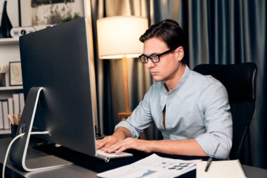 Akıllı iş adamı iş paragrafı dinamik pazarlama analizi planını analiz ediyor. Kağıt kağıtları ve bilgisayar monitörü raporlarını gece evdeki belge verileriyle karşılaştırmak için hazırlıyor. Bireysel.