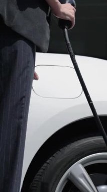 İş kadını, şehir merkezindeki ya da parktaki EV şarj istasyonundan elektrikli arabasını şarj etmek için EV şarj aleti takıyor. Çevre dostu şarj edilebilir araba şehir yaşamında alternatif enerji kullanıyor. İnceleyin.