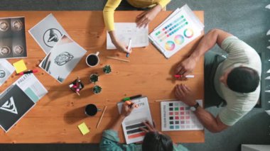 Proje yöneticisi renk paletleri seçerken tasarımcının tablete baktığı yukarıdan aşağıya hava görüntüsü. Profesyonel grafik tasarımının en üst görüntüsü ve logoya bakın. Yetenekli ekip grafikleri seçiyor. Sempozyum.