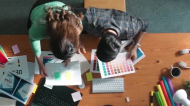 Tasarımcı yazma fikri ekrana bakarken proje yöneticisinin üst görünümü. Akıllı iş adamlarını kapat ve tasarımcı palete bakarken logo tasarımı fikrini açıkla. Sempozyum.