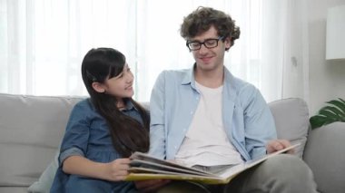 Mutlu kız babaya yaslanır hikaye anlatırken. Genç Asyalı liseli kız birlikte masal kitabı okurken ve kanepede otururken babasını arıyor. Aile eğlence konsepti. Pedagoji.