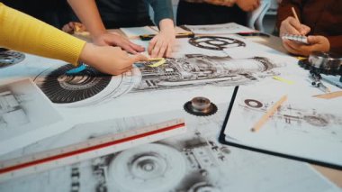 Çeşitli mühendislerden oluşan bir grup, yenilikçilik ve problem çözme üzerine odaklanmış modern bir çalışma alanında karmaşık teknik çizimler, fikirler ve içgörüler paylaşıyor. SACTR