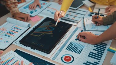 Dijital cihazlarla veri analizi yapan, işbirliği, strateji ve yenilikçi finansal çözümleri vurgulayan çeşitli profesyonellerin yer aldığı canlı bir ofis sahnesi. SACTR