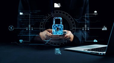 Eller teknolojideki modern güvenliği temsil eden dijital bir asma kilit tutuyor. Arka plan veri koruması ve şifreleme teknikleri gibi siber güvenlik özelliklerini gösteriyor. Dörtgen