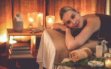 Beyaz kadın müşteri stres önleyici spa masajının keyfini çıkarıyor ve lüks otel ya da otelde sıcak mum ışığında güzellik teniyle eğleniyor. Sessiz.
