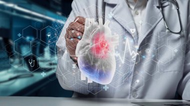 Doktor masasında tabletle otururken insan kalbi hologramına odaklan. Kalp ameliyatına hazırlanırken elinde kalemle kalp hologramına tıklıyor. İyileştirici.