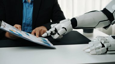 Kostümlü bir insan modern bir ofiste robot koluyla etkileşime girer ve insan zekası ile robot teknolojisi arasındaki işbirliğinin geleceğini gözler önüne serer.