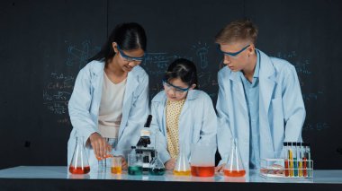 Zeki kız deney yapmak için heyecanlanan çeşitli öğrenciler iken beher kabına renkli solüsyon döker. Profesyonel bilim adamı kimyasal teoriyle kara tahtada deney yapmaya hazırlanıyor. Öğretim.