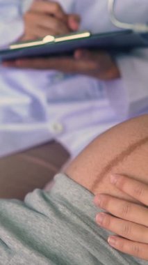 Mutlu hamile kadın, jinekolog doktoru hastanede ya da klinikte hamilelik danışmanlığı için ziyaret ediyor. Doktor, bebek ve anne sağlığı kontrolü için hamile karnı muayene ediyor. Jinekoloji konsepti.