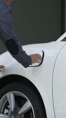 İlerici baba-kız elektrikli araç şarj istasyonundan fiş takıyor. Geleceğin çevre dostu arabası yenilenebilir temiz enerji kaynağıyla çalışıyor..