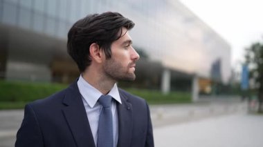 Binada dikilirken kameraya bakan yetenekli bir iş adamı. İş elbisesi giyerken kameraya gülümseyen başarılı adamın yakın çekimi. Mutlu yönetici kameraya bak. İş için. Sevinçli..