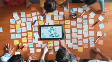 Ux Ui tasarımı kullanılarak dijital program ve yazıları tartışan ve gösteren geliştirici ekibin hava görüntüsü. İş dünyasına tepeden bakan insanlar telefon ve bilgisayar için kablo prototipi geliştiriyorlar. Sempozyum.