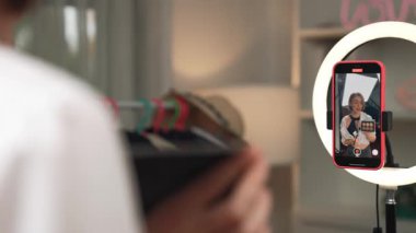 Arka plan etkileyicisi, vlog video gözden geçirme makyaj primi sosyal medya ya da blog kullanarak akıllı telefon yayınıyla canlı çekim yapıyor. İnternetteki pazarlama kaydı için kozmetik stüdyosu ışıklandırması olan kız.