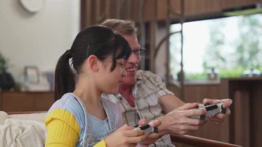 Büyükbaba ve torun birlikte konsol oyunu, eğlence medyası oynuyorlar. Eski kullanım teknolojisi yeni nesil ile iletişim kurar. Nesiller arası uçurum aile bağını güçlendirir. Uyumsuzluk.