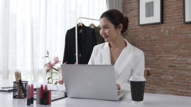 Çalışma masasında internet içeriği için dizüstü bilgisayar kullanan ya da evden çalışan genç bir iş kadını. Kıyafet ve tekstil işi pazarlama analizi. Canlılık