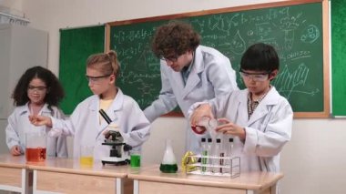 Kafkasyalı zeki öğretmen, meraklı öğrencilerin laboratuardaki deney kabına renkli sıvı dökmesini destekler. Yaratıcı çocuklar deney yapmaya ve biyokimyasal örnekleri incelemeye konsantre olurlar. Pedagoji.