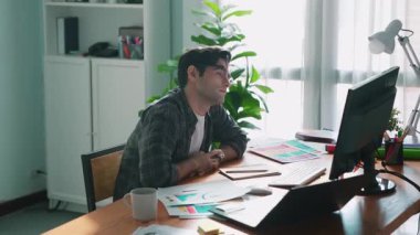 İç mimar dizüstü bilgisayarı, bilgisayarı ve kâğıdı olan toplantı masasında palete bakarken dizüstü bilgisayara bakıyor ve renk tasarlıyor. Renk tasarımı üzerinde çalışan iş adamına yakın çekim. Sempozyum.