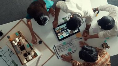 Mimar mühendis ekibinin tartıştığı ve tablet görüntüleme inşaatını planlı ve ev modeliyle toplantı masasında işaret ettiği en tepeden aşağı bakış açısı. Çeşitli tasarımcı tasarım evleri. Hizalama.