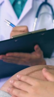 Mutlu hamile kadın, jinekolog doktoru hastanede ya da klinikte hamilelik danışmanlığı için ziyaret ediyor. Doktor, bebek ve anne sağlığı kontrolü için hamile karnı muayene ediyor. Jinekoloji konsepti.