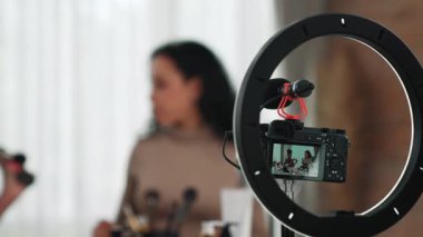 Arka plan kamera görüntüsü, iki kadın nüfuzlu kişinin canlı yayın yapan video görüntülerini kaydediyor. Makyaj, sosyal medya ya da blog. Çevrimiçi pazarlama yayını için kozmetik ürünleri olan genç bir kız.