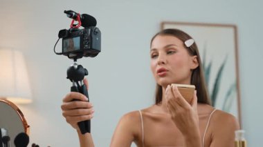 Sosyal medya için güzellik ve kozmetik video içeriği hazırlayan genç bir kadın. Güzellik blogcusu kameraya gülümserken seyircilere ve takipçilere güzellik bakımını gösteriyor. Düzenle