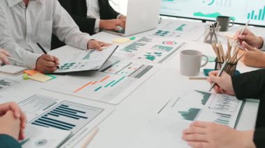 İş toplantısı sırasında profesyonellerin işbirliği yaptığı dinamik bir ofis sahnesi. Ekip üyeleri dijital ekranlar, sergilenen takım çalışması ve verileri analiz eder. SACTR