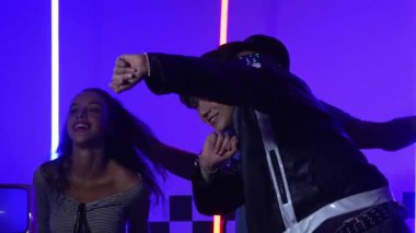 Gündelik gömlekli, gözlüklü, neon ışıkla dans eden farklı insanlar. Gece kulübünde dans ederken kameraya bakıp sokak dansı yapan çok kültürlü break dansçı. Mutluluk.