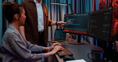 Bilgi teknolojisi geliştiricileri modern ofisteki neon ışık odasında verileri çevrimiçi olarak çalıştıran akıllı web sitesi geliştirme kodlayıcı sistemine işaret ediyorlar. İnfobahn.