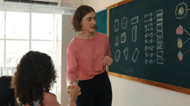 İlkokulda Afrikalı bir kızın tahtaya cevap yazmasına bakan yetenekli beyaz bir öğretmen. İlkokul sınavına cevap vermek için sınıfın önünde yürüyen profesyonel bir öğrenci. Pedagoji.