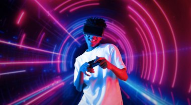 Neon soyut arka planda oyun oynarken elinde joystick tutan ve VR gözlük takan bir genç. Afrikalı adam kontrol etmeyi ve artırılmış gerçeklik teknolojisini kullanmayı seviyor. Yaratıcılık.