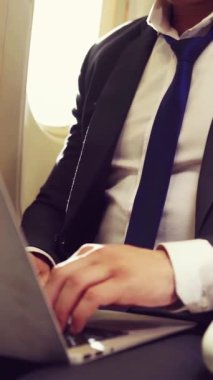 Genç iş adamı uçakta dizüstü bilgisayar kullanıyor. İş seyahati konsepti .
