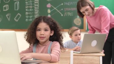 Çekici kız kodlama hızlı BTMM sınıfında kameraya bakarken mutlu öğretmen akıllı çocuk yazılım programını kontrol ediyor. Programlama kodu ve bilgisayar sistemi üzerine çeşitli öğrenci çalışmaları. Pedagoji.