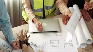 Mimari döküman, ölçüm araçları ve ahşap blokların modern ofiste etrafa saçıldığı masa üzerine planlar yapma konusunda akıllı mimar ve güvenlik mühendisi tartışması. - Yakın çekim. Tanımlama.