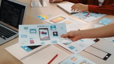 Mobil uygulama için kullanıcı arayüzü prototipini ofis çalışanlarına sunan harika bir şirket çalışanı. UX UI tasarımcısı kağıt üzerinde simge tasarımının işlevini açıklıyor. Sinerjik