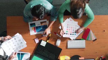 Ekip toplantısına katılıp fikir hakkında konuşurken proje yöneticisinin yazma fikrinin en üst görüntüsü. Renk paletine bakarken ve kağıda fikir yazarken profesyonel tasarımcı logosu. Sempozyum.