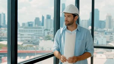 Profesyonel mühendis gökdelen manzarasına bakarken gülümsüyor. Sıradan giyinen yetenekli bir mimar, şehir manzaralı panorama penceresinin yanında dururken plan yapıyor. İzleme