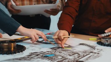 İşbirlikçi bir mühendislik projesinde çalışan çeşitli profesyonellerden oluşan bir grup, planları analiz ediyor ve yaratıcı bir hevesle modern bir çalışma alanı üzerinde araçlar kullanıyor. SACTR