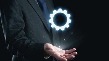 Bir işadamı, kalite ve mükemmelliği temsil eden bir ödül sembolünü elinin üstünde zarif bir şekilde sergiliyor. Parlayan yıldızlar profesyonel çabalarda tanınmayı ve başarıyı simgeliyor. Dörtgen