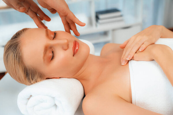 Caucasian woman enjoying relaxing anti-stress head massage and pampering facial beauty skin recreation leisure in dayspa modern light ambient at luxury resort or hotel spa salon. Quiescent