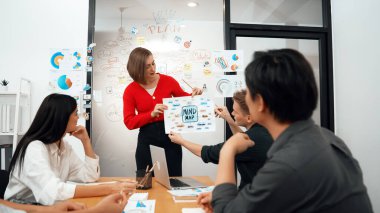 Profesyonel genç lider, iş toplantısında, stratejisini tartışan ve beyin fırtınası yapan profesyonel iş arkadaşı tarafından çevrelenmiş zihin haritasını kullanarak iş fikrini sundu. Tertemiz..