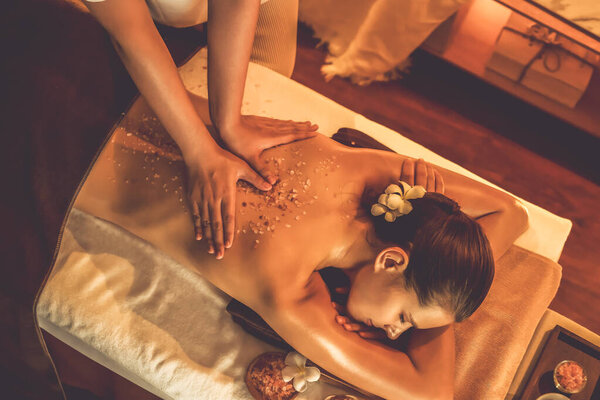 Женщина-клиент, проводящая пилинг в роскошном спа-салоне с теплым свечой окружающей среды. Косметическое лечение бальзамическим скрабом в Health spa scrub. Quiescent