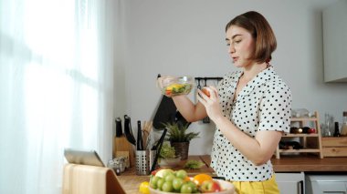 Kafkaseli anne kahvaltıda sebze pişirirken mutlu anne de modern mutfakta salata için taze malzemeler hazırlıyor. Hizmetçi sağlıklı yemek pişiriyor. Dikkat konsepti. Pedagoji.