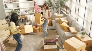 Taşınırken karton kutu taşırken birlikte dans eden mutlu çiftin üst görüntüsü. Çekici oda arkadaşı arkadaşına gösterirken kutudan bez toplarken müziğe yönelmiş. Yeniden yerleştirme. Myrmidon.